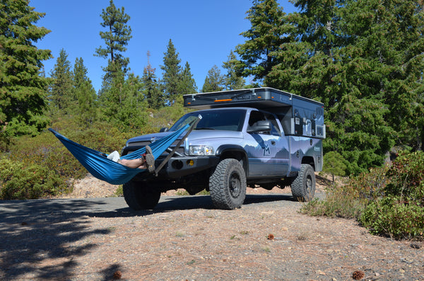 Relaxing in blue hammock on Dodge Ram with 4 Wheel Camper Hawk, custom expedition truck, thermarest hammock, nitto, KMC, Trail Ready