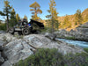 Off-road vehicle on rocky terrain with trees and a river in the background, Mammoth XL Hammock Mount and Haven Safari set up in rear hitch