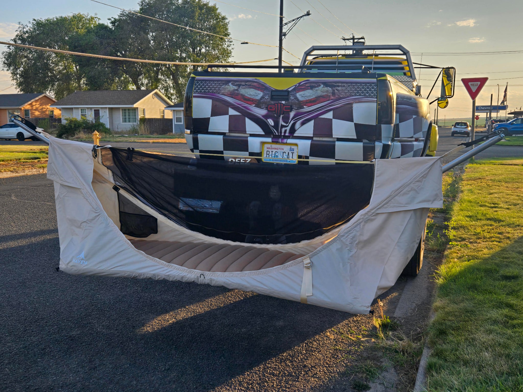 Truck with a checkered design and flag on the back, parked on a street with the Mammoth Mount and Haven Safari displayed.