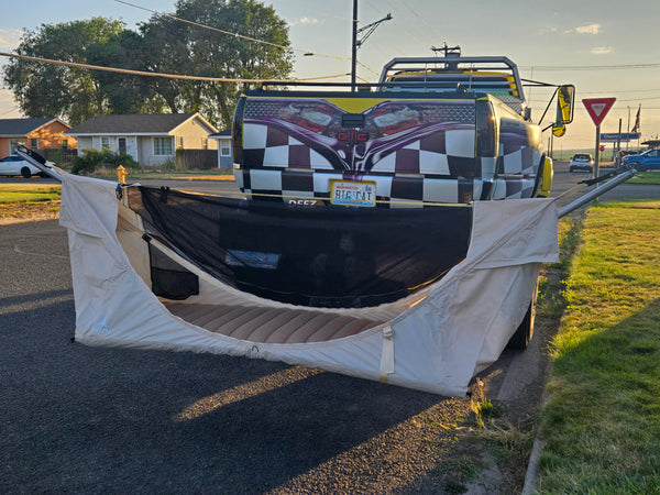Truck with a checkered design and flag on the back, parked on a street with the Mammoth Mount and Haven Safari displayed.